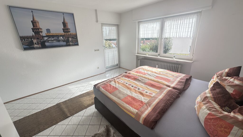 Daheim am Wasserturm – Schlafzimmer mit Balkon Alt-Text: Schlafzimmer mit Balkonzugang in Daheim am Wasserturm Untertitel: Hell & freundlich Beschreibung: Das helle Schlafzimmer überzeugt mit direktem Balkonzugang und angenehmer Atmosphäre.